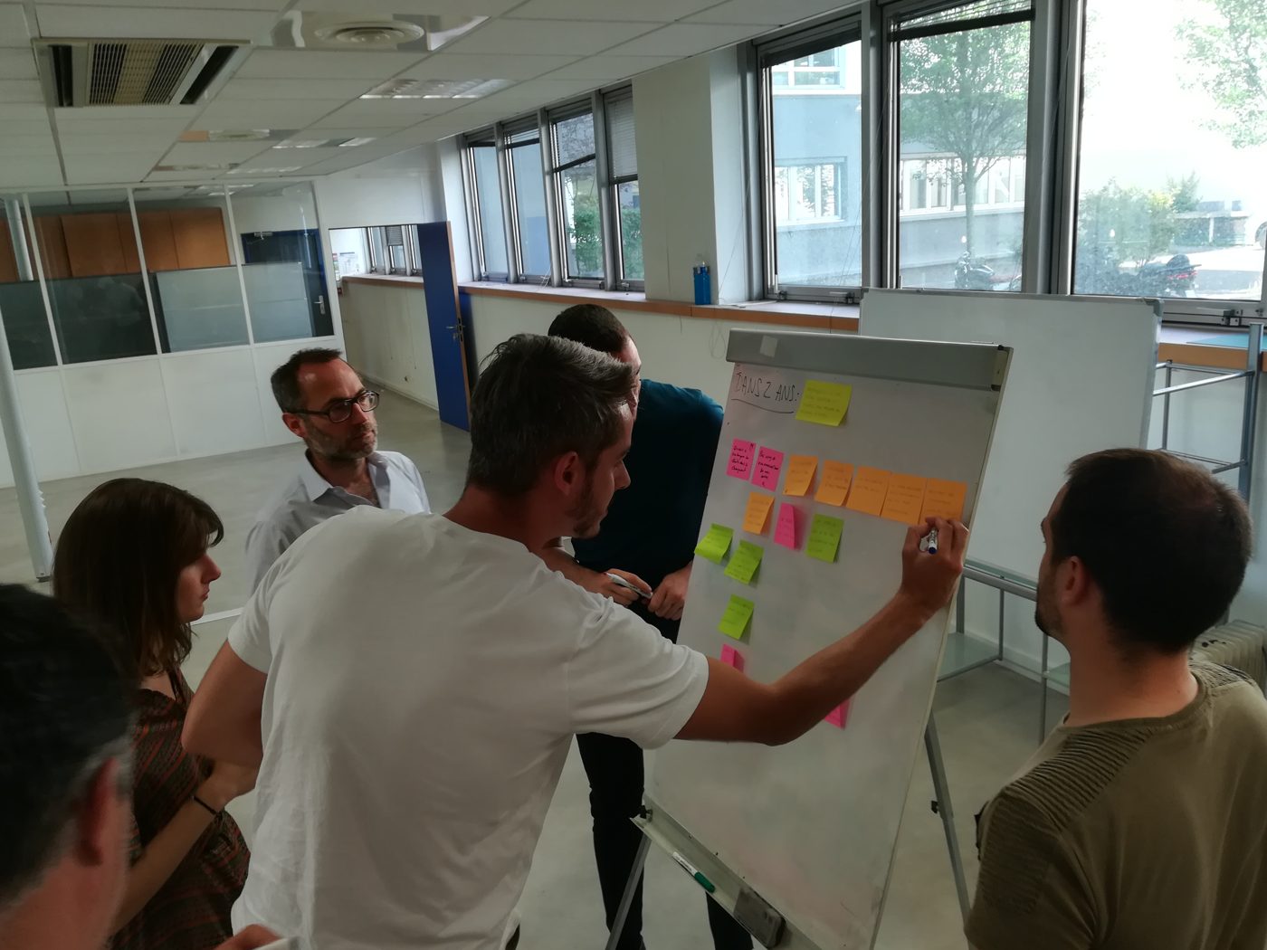 Atelier de facilitation : une équipe réunie autour d'un paperboard couvert de post-it